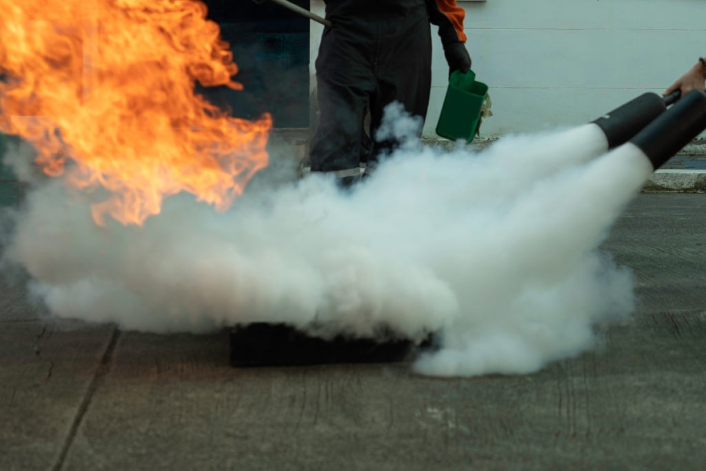 Der Mensch lehrt oder trainiert, wie man Kohlendioxid (CO2)-Feuerlöscher verwendet, um Brände aus Kraftstoff zu löschen.